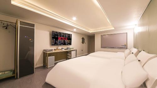 a bedroom with a large white bed and a desk at Brighton Hotel in Jeonju