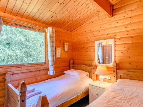 two beds in a log cabin with a window at Scandinavian Lodge - Uk37188 in Legbourne