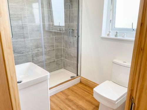 a bathroom with a shower with a toilet and a sink at Aylesbury Lodge in Halstead
