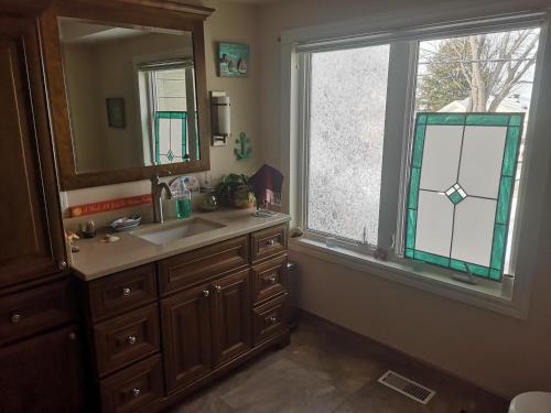 baño con lavabo, espejo y ventana en Paradise Inn en North Bay