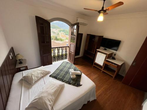 a bedroom with a bed and a balcony with a television at Pousada Casa dos Contos in Ouro Preto