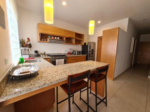 a kitchen with a counter and two bar stools at TERRARIA APARTMENT NO 6 , NEW AND GREAT LOCATiON in La Paz