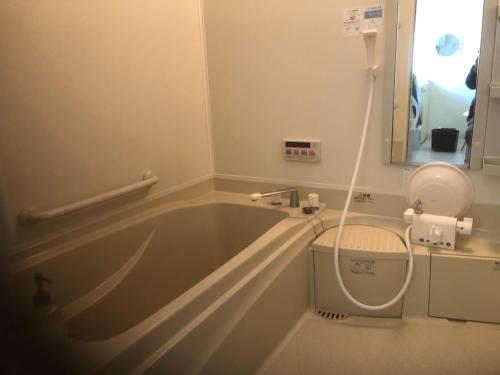 uma banheira na casa de banho com WC em art.paradigm em Kushiro