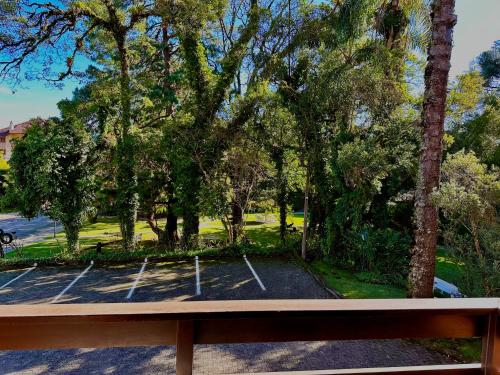 a bench in a park with trees and a parking lot at Natur Hotel - 700m da Rua Coberta in Gramado
