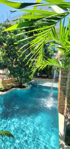 a pool with blue water and a palm tree at Ritacuba House Boutique in Santa Marta