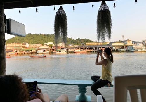 a woman taking a picture of the water with her camera at Rub Lom Chom Klong Homestay in Chumphon