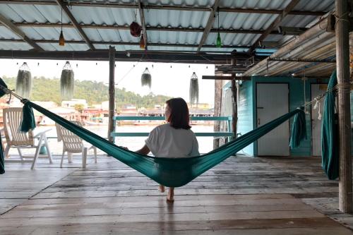 una mujer sentada en una hamaca en un muelle en Rub Lom Chom Klong Homestay, en Chumphon