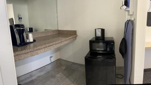 um quarto com comodidades para preparar café e um micro-ondas em Ocean Palms Motel em Pismo Beach