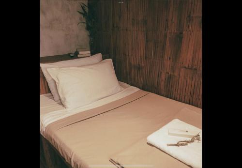 Una cama con sábanas blancas y un par de gafas. en Casitas Stay and Surf, en Baler