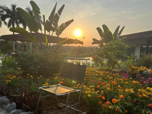 a chair in a flower garden with the sunset in the background at Eagle Bavi Resort in Ba Vì