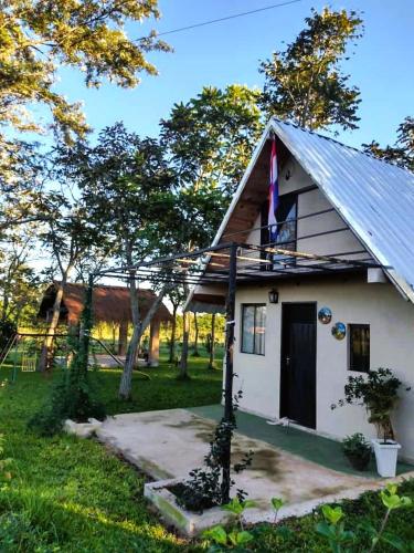 una pequeña casa blanca con una bandera. en Carmen del Paraná Sandra Hostel en Carmen del Paraná