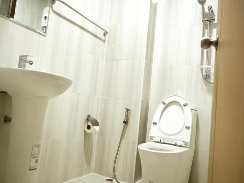 Baño blanco con aseo y lavamanos en PD Apartment Inn, en Ban Pra Dok