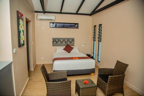ein Schlafzimmer mit einem Bett und zwei Stühlen darin in der Unterkunft Seatiki Resort Fiji On Coast in Sigatoka