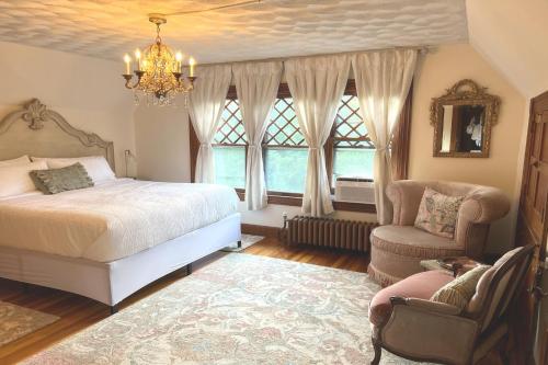 Manor House Inn في Norfolk: غرفة نوم بسرير وكرسي وثريا