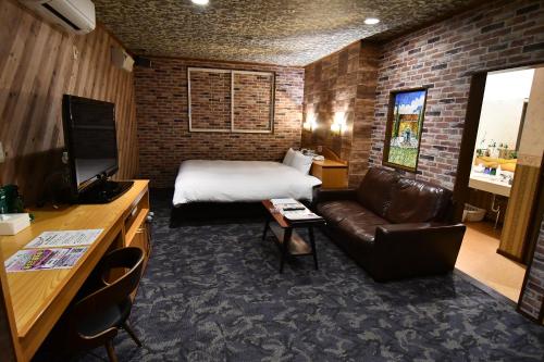 una camera d'albergo con letto e divano di 大人のホテルドルフィア a Daisen