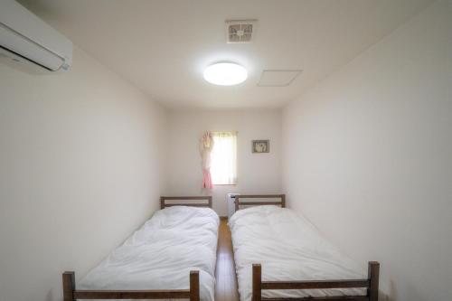 2 Betten in einem kleinen Zimmer mit Fenster in der Unterkunft 小樽民泊太田1号館 in Otaru