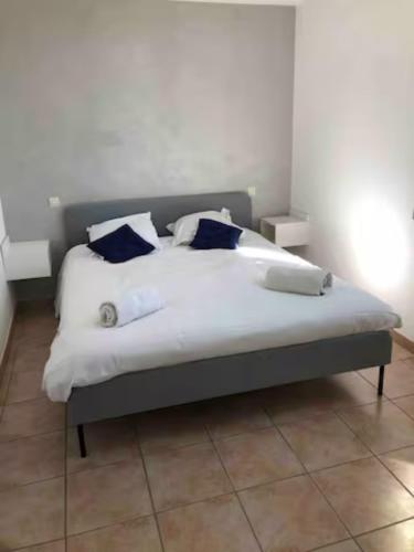 Una cama con sábanas blancas y almohadas azules. en Très bel appartement Nice vue mer en Niza