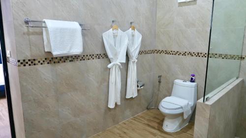 a bathroom with a shower and a toilet and towels at Jasmine Village in Rawai Beach