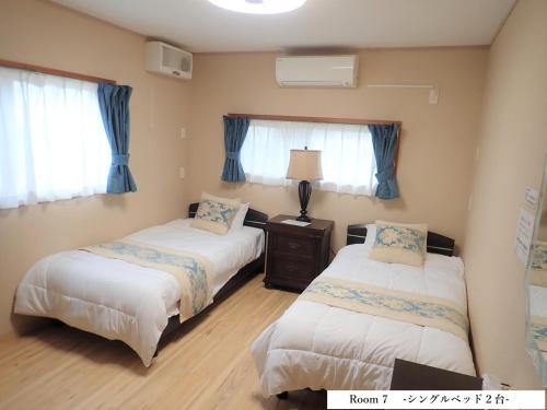 北谷 vacation house MALAPUA في شاتان: سريرين في غرفة مع ستائر زرقاء