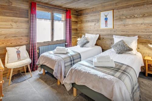 a bedroom with two beds and a chair and a window at Chalet Alyssum - OVO Network in Le Grand-Bornand