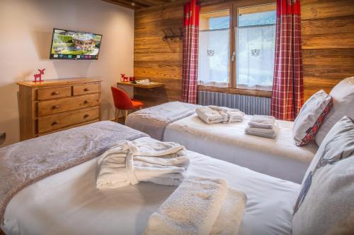 a bedroom with two beds and a dresser and a window at Chalet Alyssum - OVO Network in Le Grand-Bornand