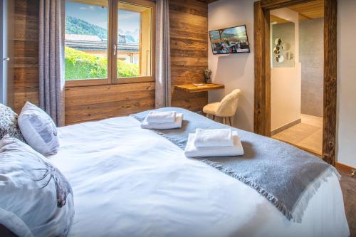 a large white bed in a room with a window at Chalet Alyssum - OVO Network in Le Grand-Bornand