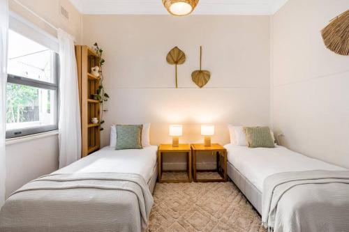 two beds in a room with a table and a window at Shirley Beach House, right in heart of Byron Bay, walking distance to town and most famous beaches in Byron Bay