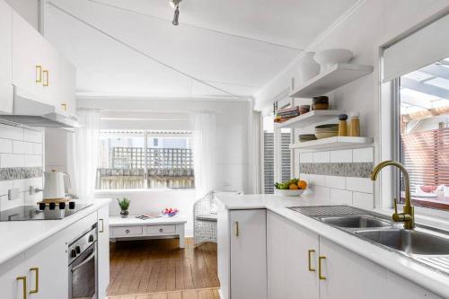 a white kitchen with white cabinets and a sink at Shirley Beach House, right in heart of Byron Bay, walking distance to town and most famous beaches in Byron Bay