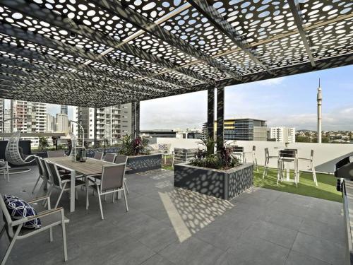 Un patio con una mesa y sillas en un tejado. en Cozy 3BR Apartment Walking Distance to GOMA, en Brisbane