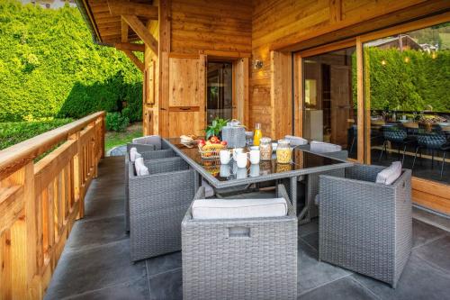 an outdoor patio with wicker chairs and a table at Chalet Alyssum - OVO Network in Le Grand-Bornand