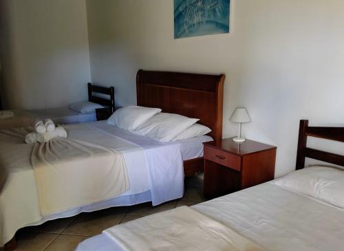 a bedroom with two beds and a table with a lamp at Pousada Casa Rosa in Alto Paraíso de Goiás