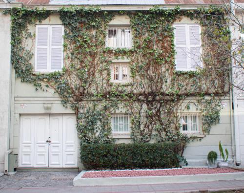 una casa cubierta de hiedra con puertas y ventanas blancas en Casa Ribera Hotel Providencia, en Santiago