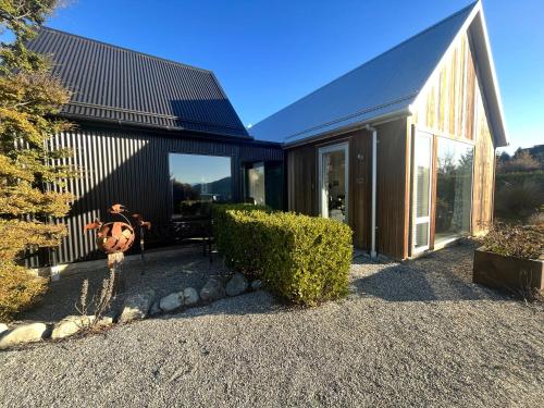 a house with a black roof and glass doors at Luxury Lake View House in Lake Tekapo