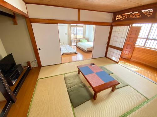 a room with a table and a room with a bed at 5LDK宜野湾ゆんたくHOUSE in Makiminato
