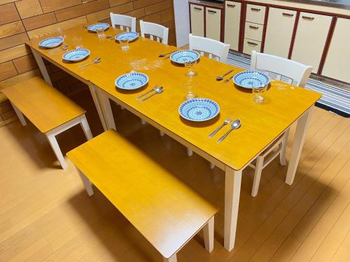 a wooden table with plates and silverware on it at 5LDK宜野湾ゆんたくHOUSE in Makiminato
