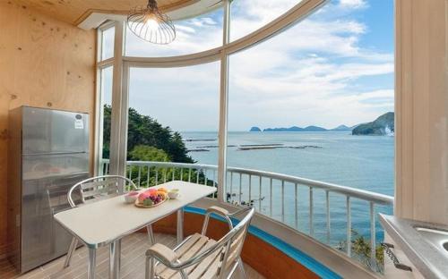 a balcony with a table and chairs and a view of the ocean at Sunbeach Pension in Geoje 