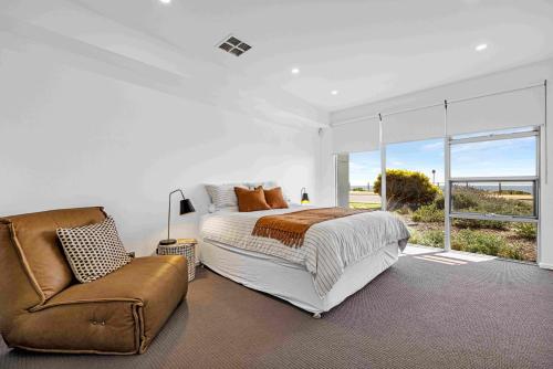 a bedroom with a bed and a chair and a window at 180 View by Wine Coast Holiday Rentals in Aldinga Beach
