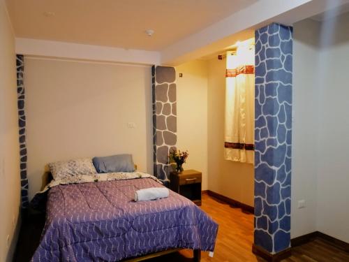 a bedroom with a bed with a purple bedspread at Cozy mountain house in Urubamba