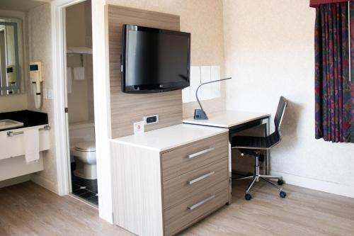 a hotel room with a desk and a tv on a wall at Discovery Inn in Hayward