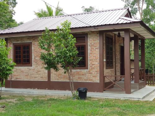 a small brick house with a metal roof at D'Impiana Riverview Chalet # Lenggong in Kampong Ulu Jepai