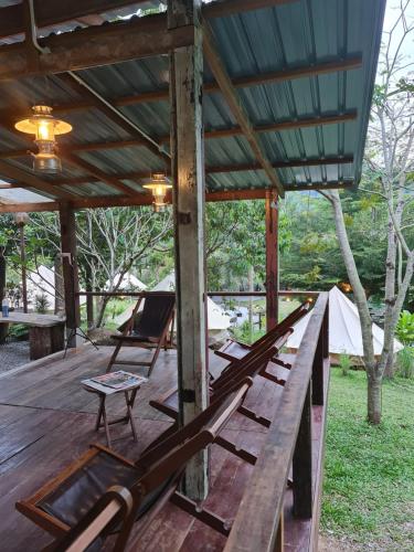 a wooden deck with lounge chairs and a tent at D'Impiana Riverview Chalet # Lenggong in Kampong Ulu Jepai