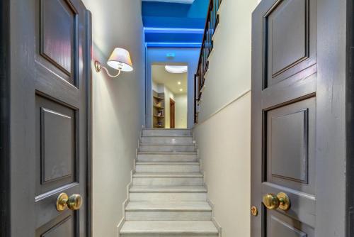 a hallway with stairs with blue ceilings and doors at Ethrion in Ermoupoli