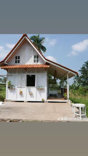 a white house with a bench in front of it at Pondok isoke in Banyuwangi