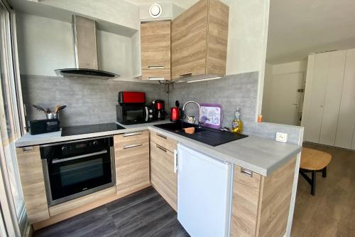 une cuisine avec un évier et une cuisinière four supérieur dans l'établissement Le saint Louis - Studio terrasse proche de la plage, au Grau-du-Roi