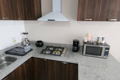 a kitchen counter with a microwave and a sink at Depa nuevo en el corazón de GDL con seguridad y alberca in Guadalajara