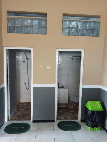 a bathroom with two doors with a shower and a toilet at Penginapan Sriwijaya Semarang in Jomblang