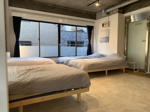 two beds in a room with a window at Spacious studio(62m2) in western Shinjuku in Tokyo