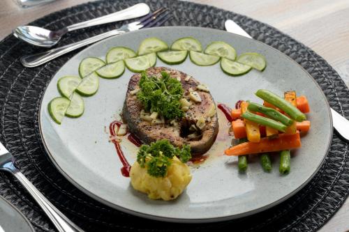 a plate of food with meat and vegetables on a table at Elephyard Retreat in Mahiyangana