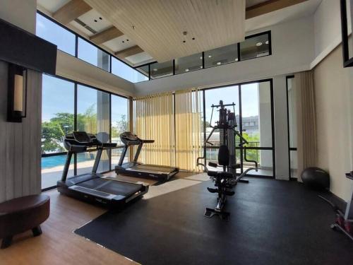 un gimnasio con cintas de correr y elípticas en una habitación con ventanas en One Residence 2 Bedroom Sea View, en Batam Centre