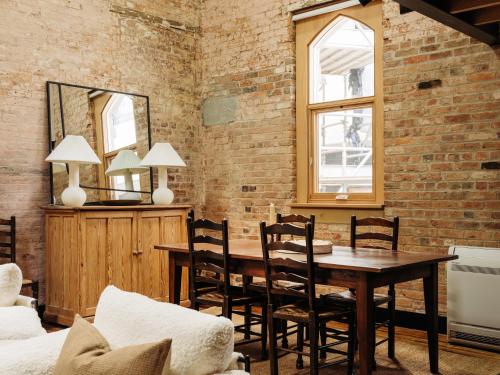 a dining room with a brick wall and a wooden table and chairs at The Rox Hobart in Hobart